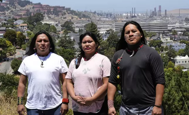 Juan Bay, president of the Waorani people of Ecuador, from left, Jhajayra Machoa Mendúa and Nadino Calapucha, a spokesperson for the Kichwa Pakkiru people, pose for a photograph as a Chevron refinery is visible in the background Thursday, June 19, 2025, in Richmond, Calif. (AP Photo/Godofredo A. Vásquez)