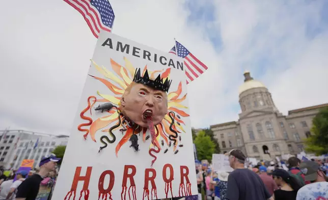 A demonstrator holds a sign during a "No Kings" protest, Saturday, June 14, 2025, in Atlanta. (AP Photo/Mike Stewart)