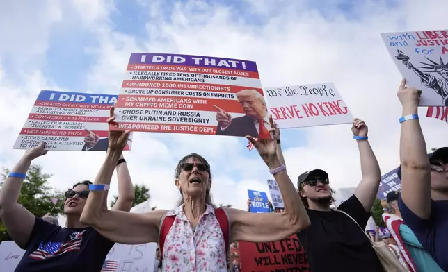 Demonstrators holds a signs during a "No Kings" protest, Saturday, June 14, 2025, in Atlanta. (AP Photo/Mike Stewart)