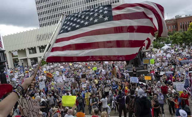 A person waves an American flag as demonstrators gather at Metro Hall during a "No Kings" protest on Saturday, June 14, 2025, in Louisville, Ky. (AP Photo/Jon Cherry)