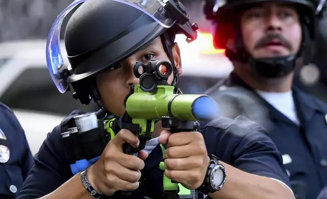 A law enforcement officer fires a less-lethal projectile during a protest Saturday, June 14, 2025, in Los Angeles. (AP Photo/Noah Berger)