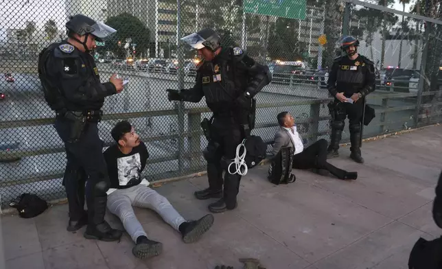 California Highway Patrol officers arrest two men after a dispersal order during a protest Saturday, June 14, 2025, in Los Angeles. (AP Photo/Ethan Swope)