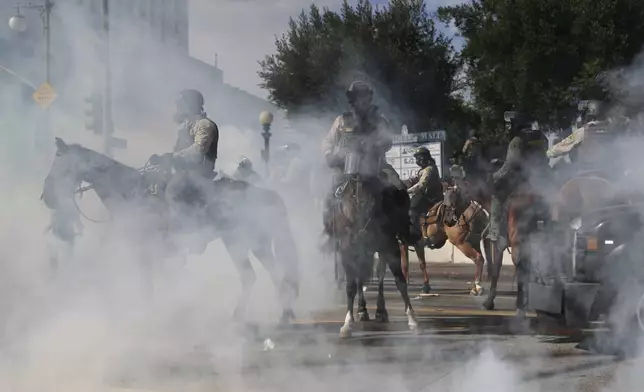 EDS NOTE: OBSCENITY - Tear gas surrounds law enforcement officers on horseback during a protest Saturday, June 14, 2025, in Los Angeles. (AP Photo/Ethan Swope)