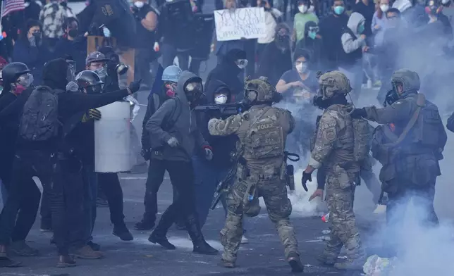 U.S. Customs and Border Protection agents standoff against demonstrators as tear gas fills the air outside the U.S. Immigration and Customs building during a protest Saturday, June 14, 2025, in Portland, Ore. (AP Photo/Jenny Kane)