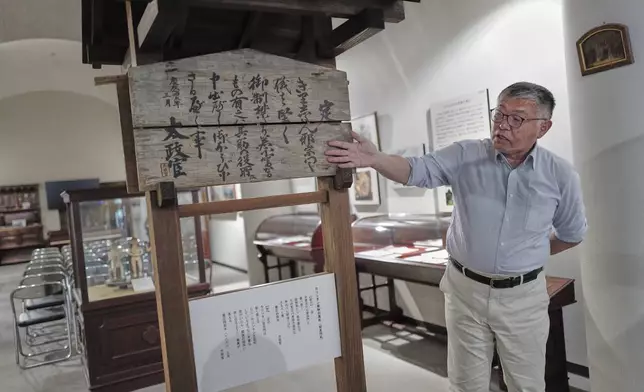 Shigeo Nakazono, a folklore studies expert specializing in the hidden Christians and head of the Ikitsuki Island Museum "Shima no Yakata" explains an official edict board issued to ban Christianity during Japan's Edo period displayed at the museum at Ikitsuki Island in Hirado, southern Japan, Sunday, April 27, 2025. (AP Photo/Eugene Hoshiko)
