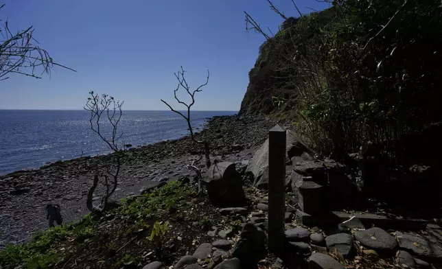 A fisherman, left, walks on a seashore of Ikitsuki island in Hirado, southern Japan, Monday, April 28, 2025, as seen from a sacred site where it's believed a grave was built after Catholic family members were martyred. (AP Photo/Hiro Komae)