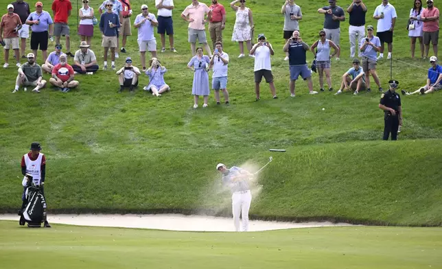 Scottie Scheffler, center, hits his second shot from the bunker to the water on the 17th hole during the second round of the Travelers Championship golf tournament at TPC River Highlands, Friday, June 20, 2025, in Cromwell, Conn. (AP Photo/Jessica Hill)