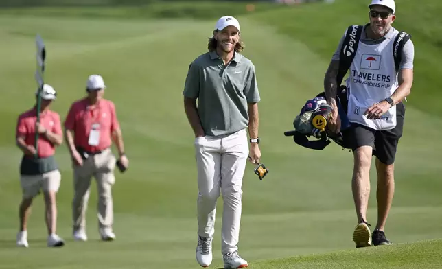 Tommy Fleetwood, center, of England, smiles as he approaches the 18th green during the second round of the Travelers Championship golf tournament at TPC River Highlands, Friday, June 20, 2025, in Cromwell, Conn. (AP Photo/Jessica Hill)