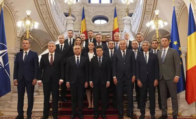 Romanian President Nicusor Dan, center right, and Prime Minister Ilie Bolojan, center left, pose for a photograph with the new government after a swearing in ceremony at the Cotroceni Presidential Palace in Bucharest, Romania, Monday, June 23, 2025. (AP Photo/Andreea Alexandru)