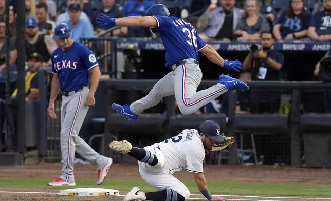 Texas Rangers' Wyatt Langford (36) leaps over Tampa Bay Rays first baseman Jonathan Aranda as he reaches first base safely on a throwing error by Jose Caballero during the first inning of a baseball game Wednesday, June 4, 2025, in Tampa, Fla. (AP Photo/Chris O'Meara)