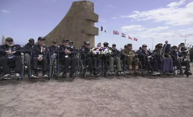 World War II veterans, mostly centenarians, who traveled as a group to France with the non-profit Best Defense Foundation, pose for a photo on Monday, June 2, 2025, at a memorial on Omaha beach, which was one of the D-D-day invasion spots on June 6, 1944. (AP Photo/John Leicester)