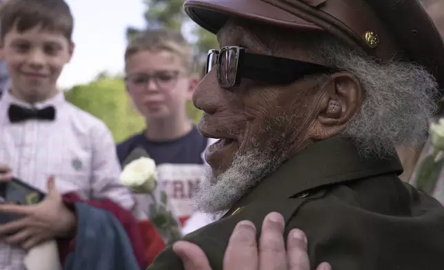 Arlester Brown, a 101-year-old veteran of World War II who served in a laundry unit that accompanied the Allied advances through France and the Low Countries and into Nazi Germany, regales French children with his stories during a visit on Monday in Colleville-sur-Mer, June 2, 2025, to the Normandy American Cemetery that is the final resting place for nearly 9,400 American war dead and which overlooks Omaha beach, one of the D-D-day invasion zones on June 6, 1944. (AP Photo/John Leicester)
