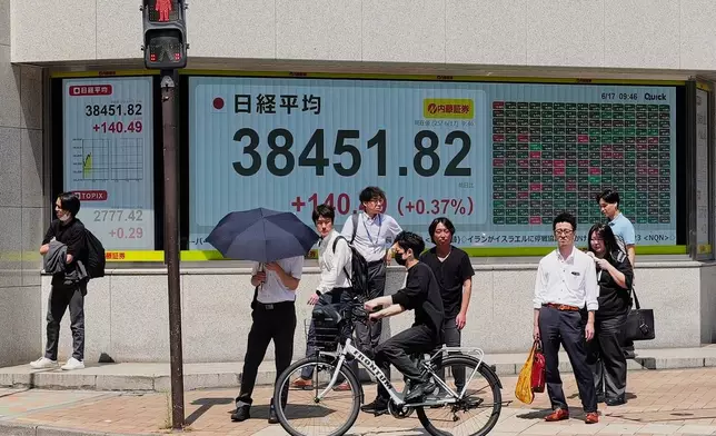 People stand in front of an electronic stock board showing Japan's Nikkei index at a securities firm Tuesday, June 17, 2025, in Tokyo. (AP Photo/Eugene Hoshiko)
