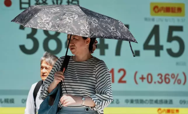 People walk in front of an electronic stock board showing Japan's Nikkei index at a securities firm Tuesday, June 17, 2025, in Tokyo. (AP Photo/Eugene Hoshiko)