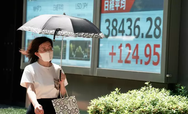 A person walks in front of an electronic stock board showing Japan's Nikkei index at a securities firm Tuesday, June 17, 2025, in Tokyo. (AP Photo/Eugene Hoshiko)