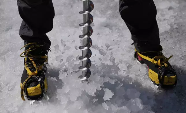 Matthias Huss, of the Federal Institute of Technology in Zurich and glacier monitoring group GLAMOS, drills holes into the Rhone Glacier near Goms, Switzerland, June 10, 2025. (AP Photo/Matthias Schrader)