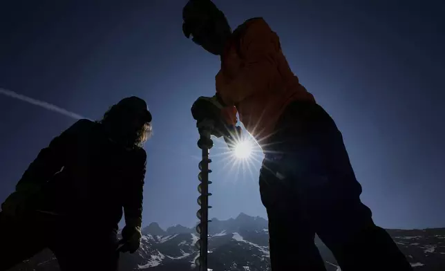Matthias Huss, of the Federal Institute of Technology in Zurich and glacier monitoring group GLAMOS, right, drills holes into the Rhone Glacier near Goms, Switzerland, June 10, 2025. (AP Photo/Matthias Schrader)