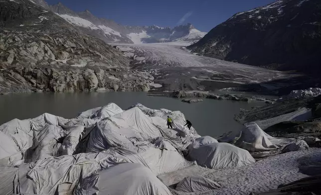 Workers prepare sheets to cover the Rhone Glacier near Goms, Switzerland, June 10, 2025. (AP Photo/Matthias Schrader)