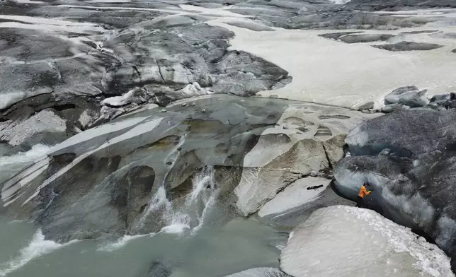 Matthias Huss, of the Federal Institute of Technology in Zurich and glacier monitoring group GLAMOS, drills holes into the Rhone Glacier near Goms, Switzerland, June 10, 2025. (AP Photo/Matthias Schrader)