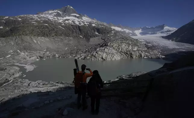 Matthias Huss, of the Federal Institute of Technology in Zurich and glacier monitoring group GLAMOS, and Monica Ursina Jaeger arrive at the Rhone Glacier near Goms, Switzerland, June 10, 2025. (AP Photo/Matthias Schrader)