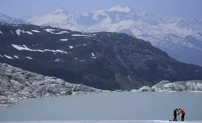 Matthias Huss, of the Federal Institute of Technology in Zurich and glacier monitoring group GLAMOS, and Monica Ursina Jaeger prepare a camera at the Rhone Glacier near Goms, Switzerland, June 10, 2025. (AP Photo/Matthias Schrader)