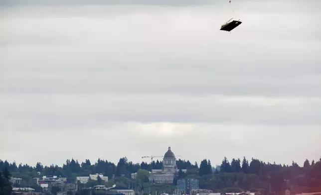 With the Washington Capitol building in the background, an abandoned ship is airlifted on Wednesday, June 4, 2025, in Olympia, Wash. (AP Photo/Jenny Kane)