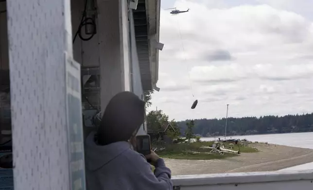 Lucy Trout, from Olympia, Wash., watches as an abandoned ship is transported to shore on Wednesday, June 4, 2025, in Olympia, Wash. (AP Photo/Jenny Kane)
