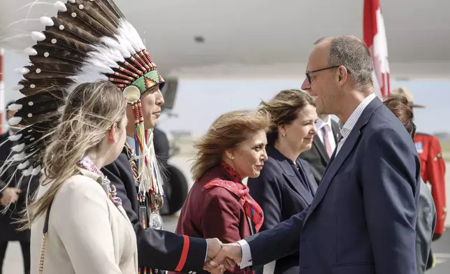 German Chancellor Friedrich Merz, right, is greeted by Steven Crowchild, second left, of the Tsuut'ina First Nation, as he arrives in Calgary, Alberta, Sunday, June 15, 2025, to attend the G7 Leaders meeting taking place in Kananaskis. (Jeff McIntosh/The Canadian Press via AP)