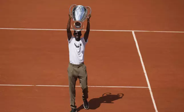 PSG's soccer player Ousmane Dembele presents the Champions League trophy during the French Tennis Open at the Roland-Garros stadium in Paris, Monday, June 2, 2025. (AP Photo/Christophe Ena)
