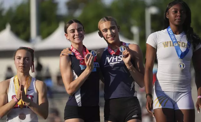 Flanked by fourth-place winner Ellie McCuskey-Hay, left, and first-place winner Loren Webster, right, second-place winners AB Hernandez, center right, and Brooke White share the podium during a medal ceremony for the long jump at the California high school track-and-field championships in Clovis, Calif., Saturday, May 31, 2025. (AP Photo/Jae C. Hong)