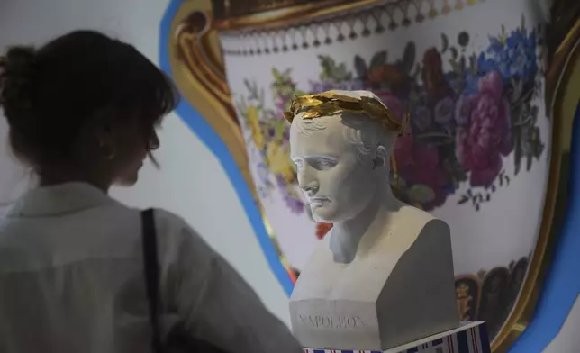 A woman watches a Napoleon bust in an exhibition of Napoleon's belongings created by French designer Jean-Charles de Castelbajac at the Sotheby's auction house in Paris Thursday, June 19, 2025 in Paris. (AP Photo/Christophe Ena)