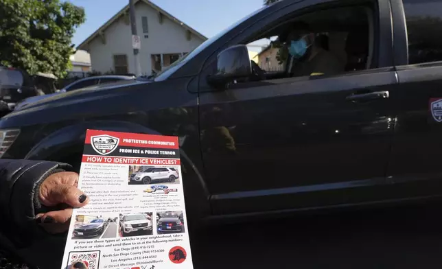 A member of the Union del Barrio, a grassroots political organization, distributes a "How to Identify ICE vehicles" flyer to people living in Los Angeles, Monday, June 16, 2025. (AP Photo/Damian Dovarganes)
