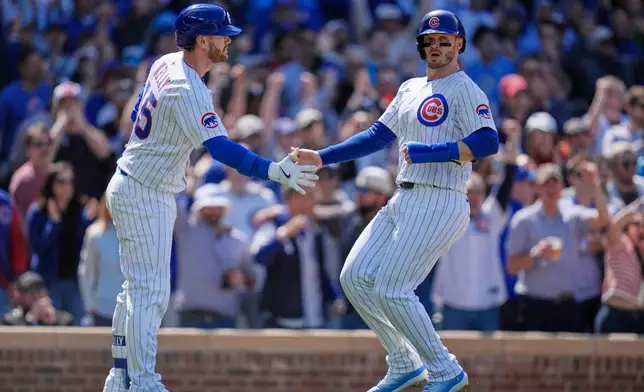 Chicago Cubs' Happ, right, slaps hands with Carson Kelly (15) after scoring on a double by designated hitter Seiya Suzuki (27) during the eighth inning of a baseball game against the Cincinnati Reds, Saturday, May 31, 2025, in Chicago. (AP Photo/Erin Hooley)
