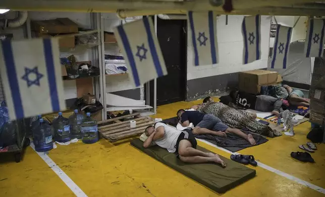 People rest and as they take shelter in an underground parking garage as a precaution against possible Iranian missile attacks, in Tel Aviv, Israel, Tuesday, June 24, 2025. (AP Photo/Ohad Zwigenberg)