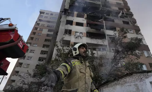 A firefighter calls out his colleagues at the scene of an explosion in a residence compound in northern Tehran, Iran, Friday, June 13, 2025. (AP Photo/Vahid Salemi)