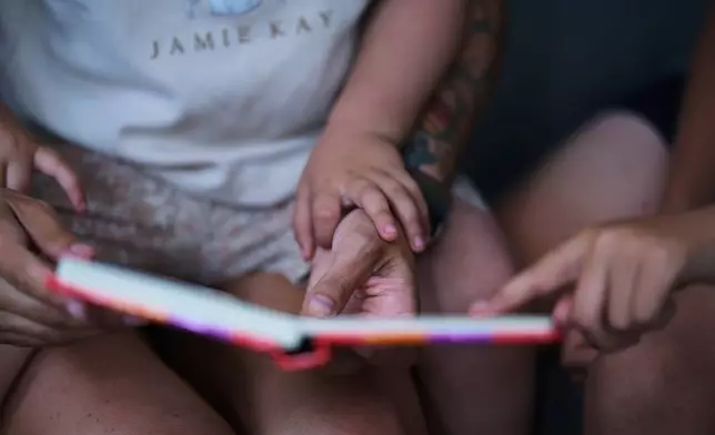 Eileen Lamb, who was diagnosed with Autism as an adult, reads with her daughter Billie and son Jude, who also has autism, Monday, May 12, 2025, in Austin, Texas. (AP Photo/Eric Gay)