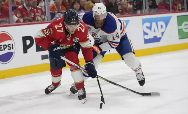 FILE - Florida Panthers center Eetu Luostarinen (27) and Edmonton Oilers defenseman Mattias Ekholm (14) go after the puck during the second period of Game 7 of the NHL hockey Stanley Cup Final, Monday, June 24, 2024, in Sunrise, Fla. (AP Photo/Wilfredo Lee, File)