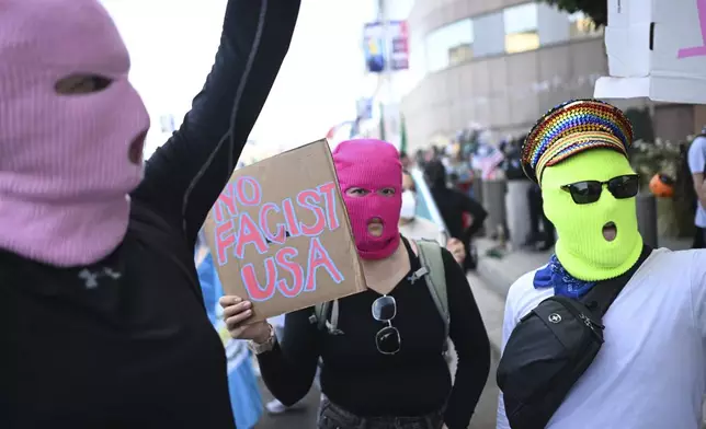 Demonstrators wearing masks hold signs outside the Federal Building during a protest on Friday, June 13, 2025, in Los Angeles. (AP Photo/Wally Skalij)
