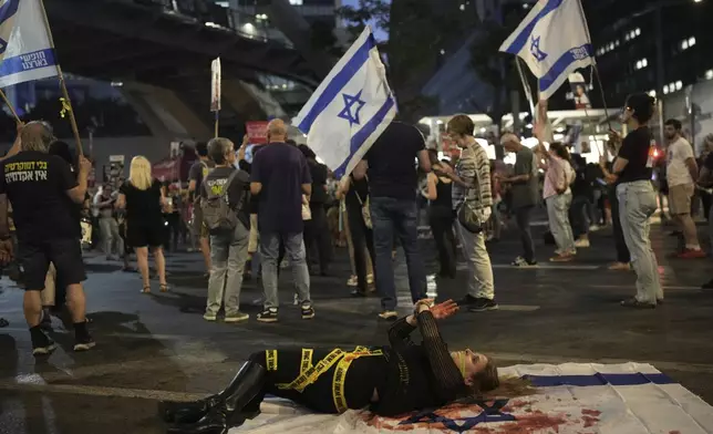 A demonstrator takes part in a performance during a protest against Prime Minister Benjamin Netanyahu's government and call for the release of hostages held in the Gaza Strip by the Hamas militant group, in Tel Aviv, Israel, Saturday, June 7, 2025. (AP Photo/Ohad Zwigenberg)