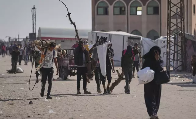 Displaced Palestinians carrying wood and other items in Rafah, southern Gaza Strip on Saturday, June 7, 2025. (AP Photo/Jehad Alshrafi)