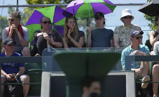Spectators shelter from the sun on day one at the Wimbledon Tennis Championships in London, Monday, June 30, 2025. (AP Photo/Joanna Chan)