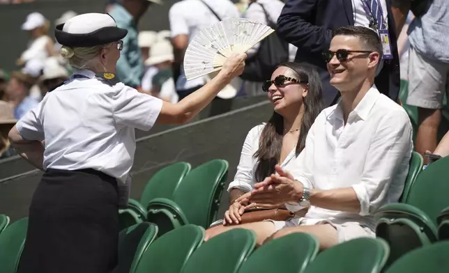 A steward fans spectators sitting on Centre Court on day one of the Wimbledon Tennis Championships in London, Monday, June 30, 2025. (AP Photo/Alastair Grant)