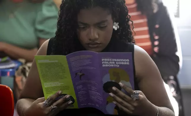 Mayra dos Santos reads a leaflet titled in Portuguese; "We need to talk about abortion", during a circle conversation to provide guidance on reproductive rights, at the Women's House of Mare in Rio de Janeiro, Tuesday, May 20, 2025. (AP Photo/Bruna Prado)