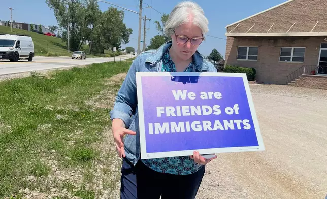 Sara Schulte-Bukowinski, a faith leader in Omaha, Neb., holds a sign protesting an immigration raid, Tuesday, June 10, 2025, at Glenn Valley Foods, a meat packaging plant in south Omaha. (AP Photo/Margery A. Beck)
