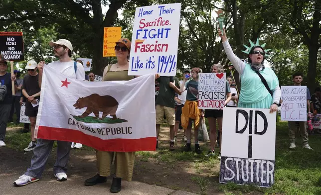 Demonstrators carry signs as they participate in a protest taking place on the day of a military parade commemorating the Army's 250th anniversary, coinciding with President Donald Trump's 79th birthday, Saturday, June 14, 2025, in Washington. (AP Photo/Evan Vucci)