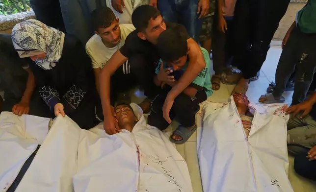 EDS NOTE: GRAPHIC CONTENT - Palestinians mourn over the bodies of people who were killed while returning from one of the Gaza Humanitarian Foundation distribution centers operated by the U.S.-backed organization, according to Nasser Hospital, during their funeral in Khan Younis, Monday, June 30, 2025. (AP Photo/Mariam Dagga)