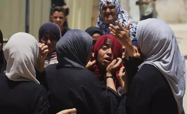 Palestinians women mourn during the funeral of people who were killed while returning from one of the Gaza Humanitarian Foundation distribution centers operated by the U.S.-backed organization, according to Nasser Hospital, during their funerals in Khan Younis, Monday, June 30, 2025. (AP Photo/Mariam Dagga)