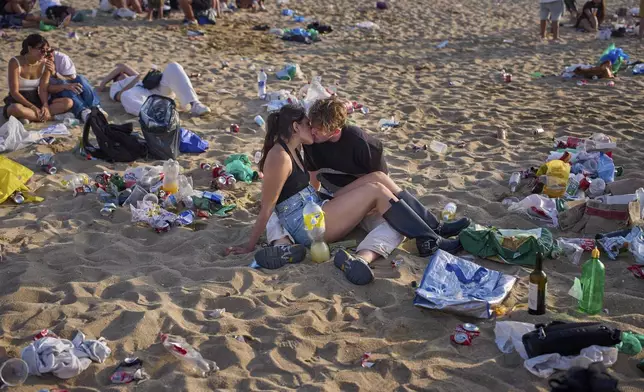 A couple kiss as they celebrate the night of San Juan on the beach, watching the sunrise that coincides with the summer solstice, marking the arrival of the summer season in Barcelona, Spain, Tuesday, June 24, 2025. (AP Photo/Emilio Morenatti)
