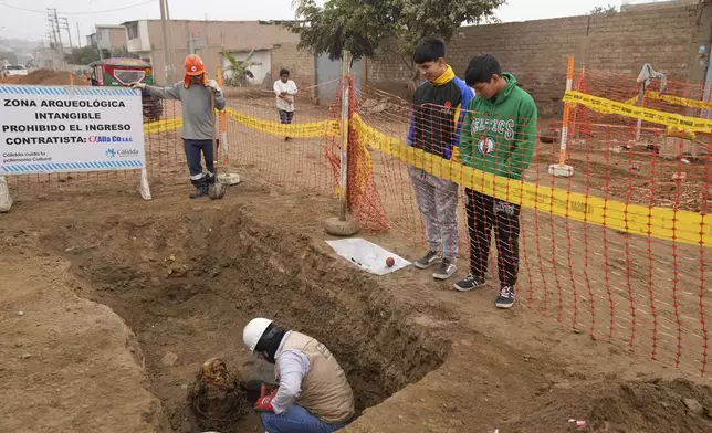 Archaeologist Jose Aliaga excavates an ancient mummy, which he said is a female from the pre-Inca Chancay culture, that was discovered by city workers who were digging a natural gas line for the company Calidda in the district of Puente Piedra on the outskirts of Lima, Peru, Wednesday, June 18, 2025. (AP Photo/Martin Mejia)