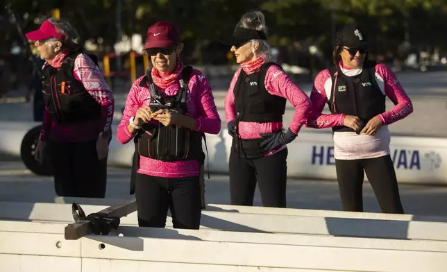 The Rosas Va'a Hawaiian canoeing team, whose members are women who have undergone cancer treatment, gather on Charitas Beach to train on the water in Niteroi, Rio de Janeiro state, Thursday, June 26, 2025. (AP Photo/Bruna Prado)